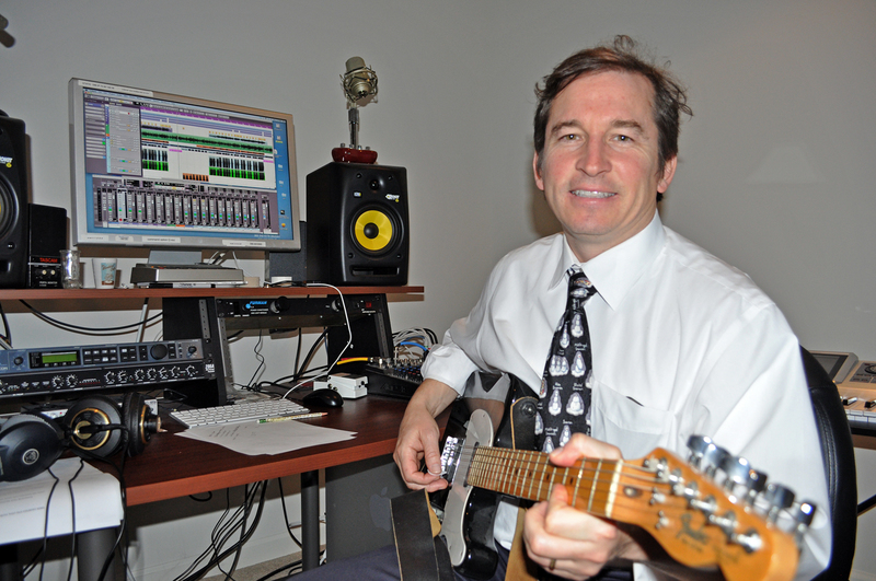 Dr. Jonathan Patterson plays guitar in the recording studio in the basement of his Milton home. BY NICK ROTH