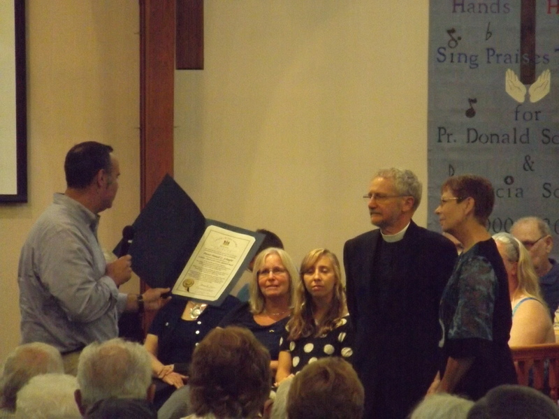 Delaware Sen. Ernie Lopez, R-Lewes, left, reads a proclamation to Pastor Donald and Marcia Schaefer commending their community service as the choir looks on. SOURCE SUBMITTED