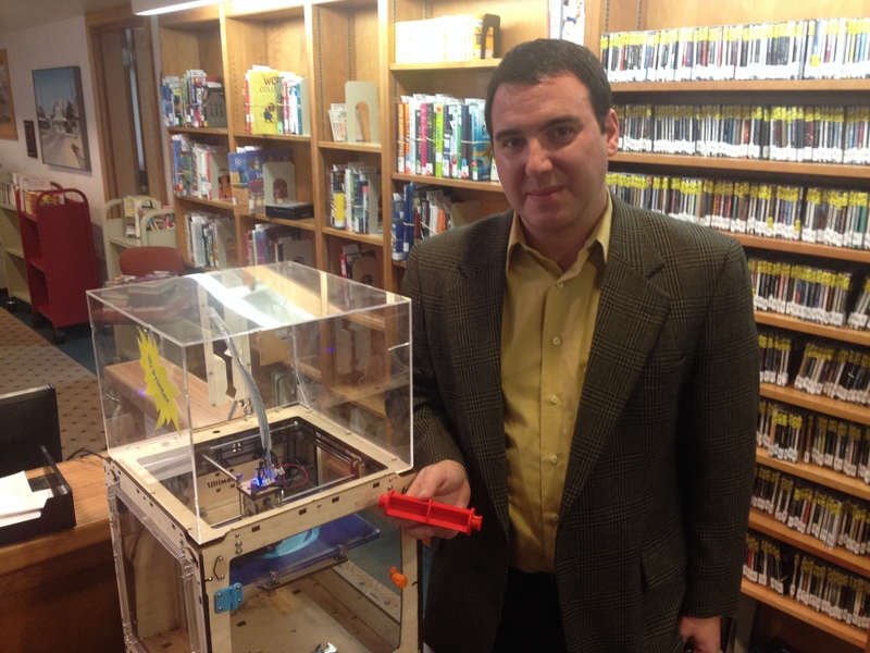 Lewes Public Library Director Ed Goyda shows the red plastic toilet paper roll holder printed on the library's 3D printer. BY DENNIS FORNEY
