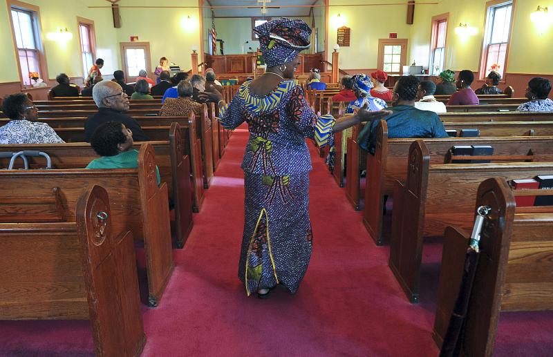 The Rev. Wassetta Moses walks down the aisle with a Liberian dress and headgear.