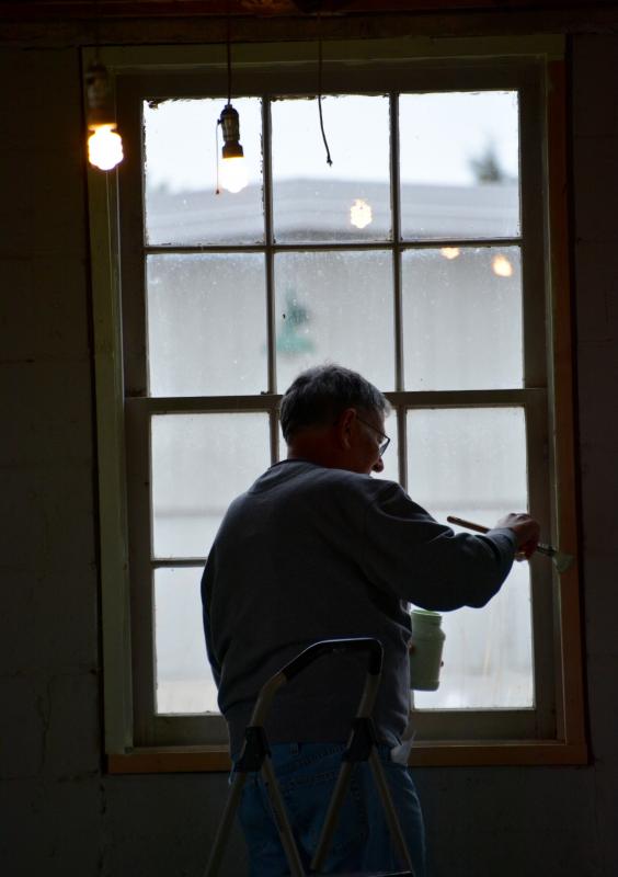 Rich Ross is silhouetted in a window as he paints a new frame in one of the fort’s 76-year-old barracks.