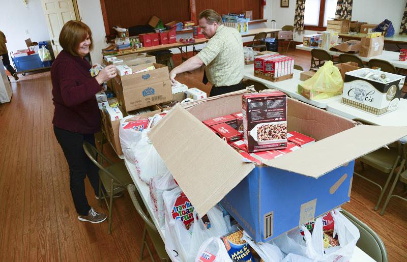 Donna Murawski and Lawrence Bivens add newly-donated stuffing to pantry boxes.