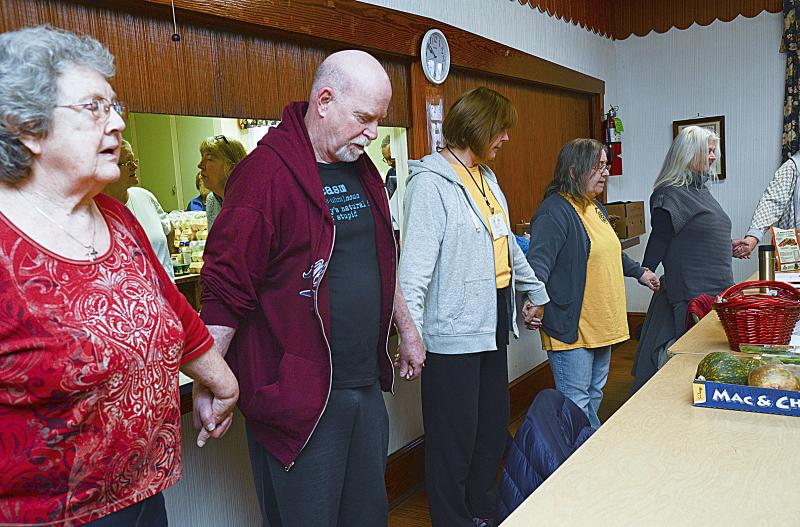 Volunteers line up for a prayer before the pantry opens for business.