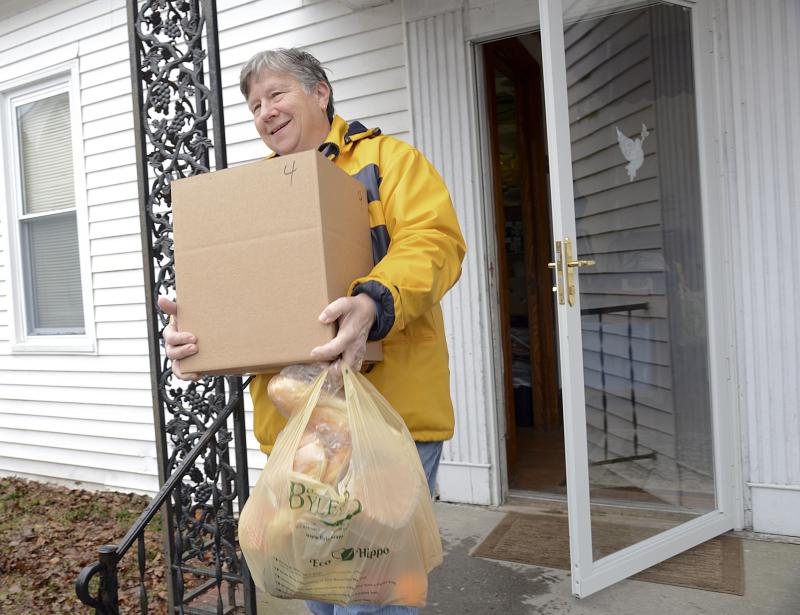 Sue Stringfield carries food for four to the car for a client.