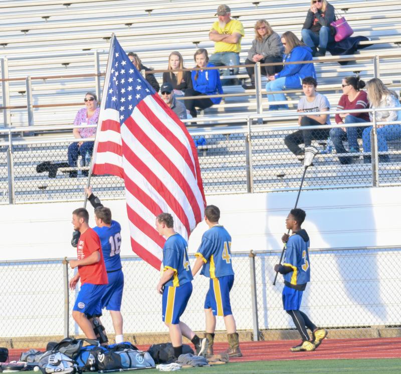 Sussex Central athletes run the American flag down the track during the early moments of the varsity game. DAVE FREDERICK PHOTOS
