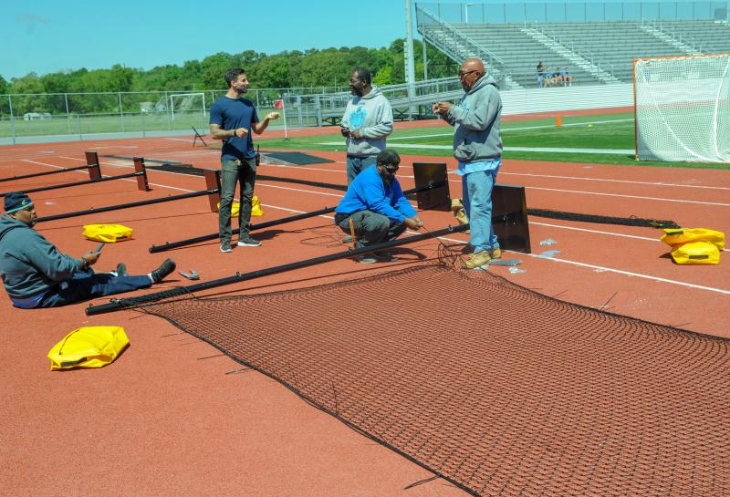 Cape’s custodial “Too Live Crew” members are erecting safety netting in time for state tournament boys’ lacrosse games.
