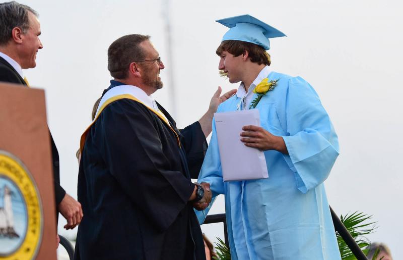 Proud teacher and dad Mike Tkach presents his son, Patrick, his diploma.