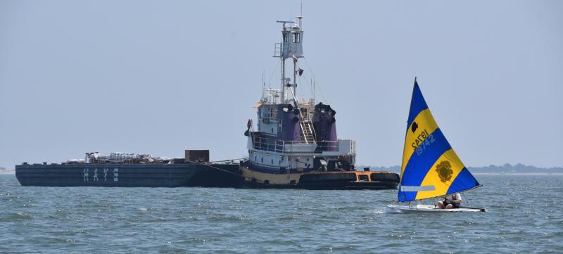 A Sunfish sails near the barge used to launch the Lewes fireworks. RON MACARTHUR PHOTO