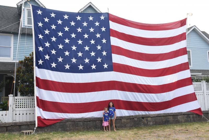 A steady stream of people take photos in front of the Lewes Flag, across from Dairy Queen. Taking their turn are Sloane, 4, and Claire Ziga, 9, of Havertown, Pa.