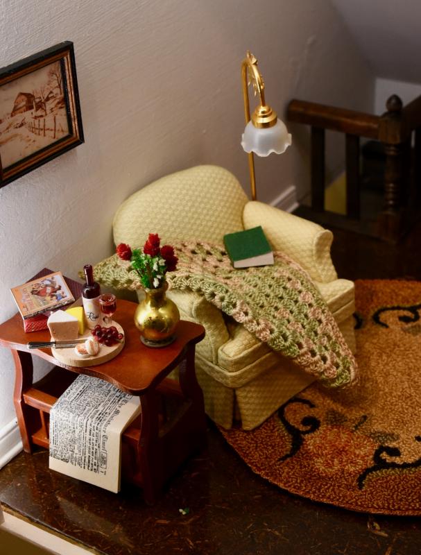 The miniature crochet blanket was hand made by Liz’s mother. The attention to detail is evident in this room complete with wine and cheese, flowers and a newspaper.