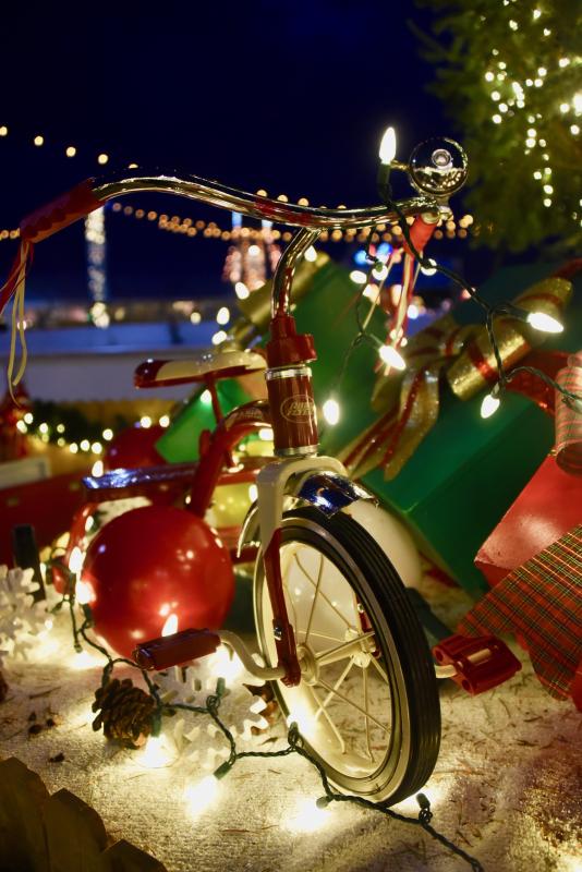 A decorated tricycle is bright and shiny under the Wonderfest Christmas tree.