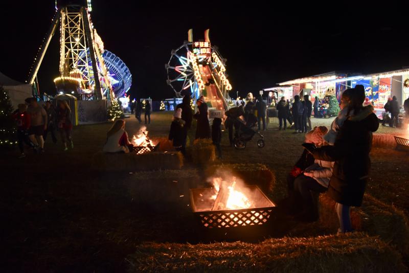 Fires provide warmth in the area set aside for carnival rides and games.
