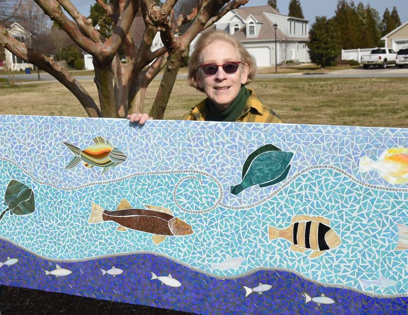 Artist Lorelei Meanor displays a finished panel of the mosaic.