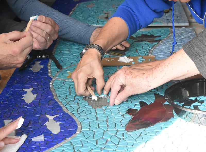 Volunteers take on the tedious task of placing individual pieces on the mosaic.
