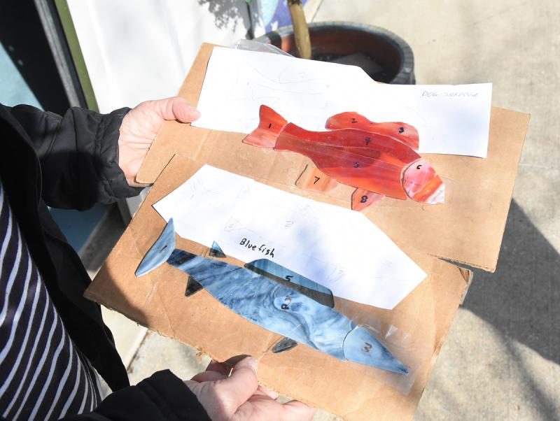 Stained glass fish are brought to be added to the project.