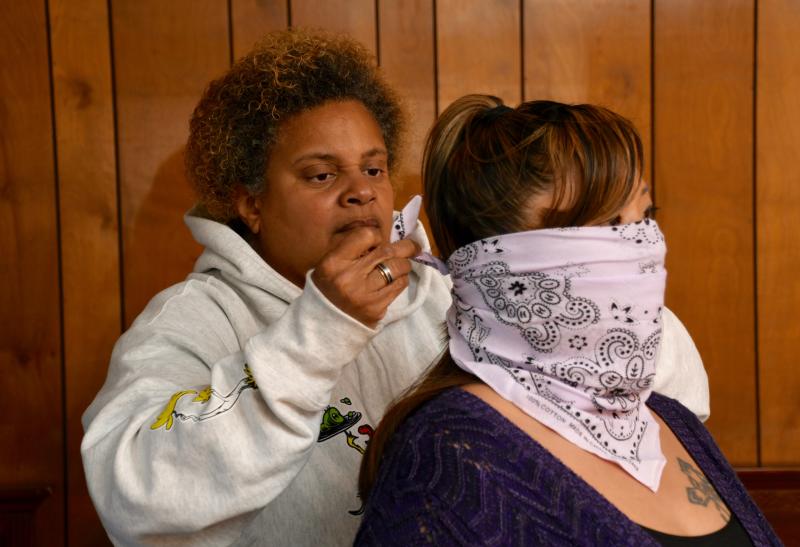 Immanuel Shelter homeless shelter program coordinator Toni Short ties a protective mask on one of her clients.