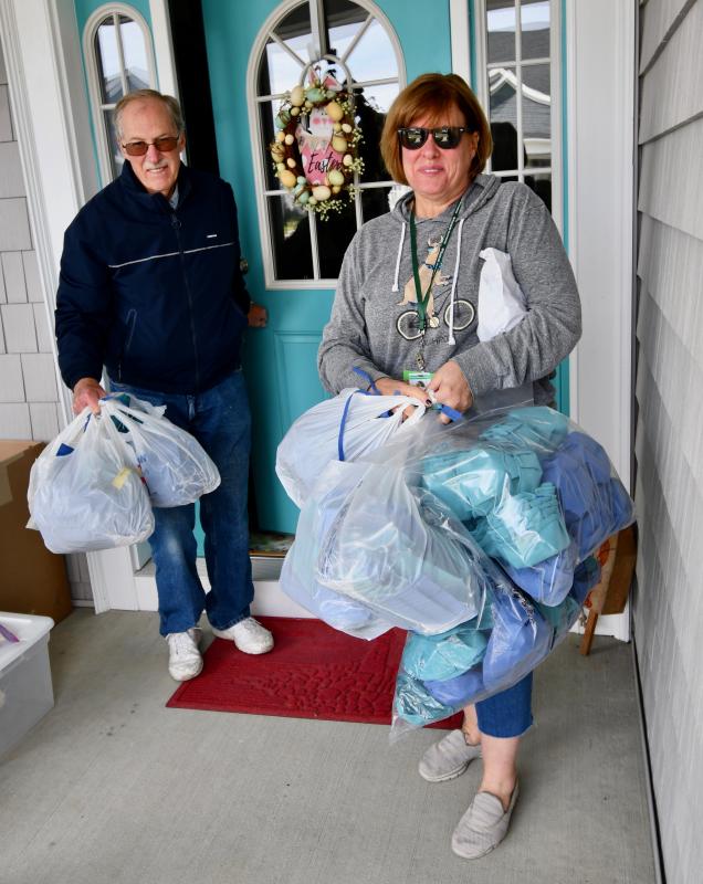 Nanticoke Memorial Hospital’s Kim Ostroski gets help from Dalton Semmel of Lewes as they carry large bags of masks to be delivered to the Seaford hospital.