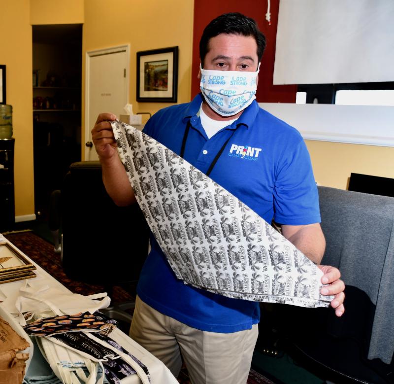 Jay Diaz explains how protective bandanas are printed and sewn. Orders for masks and bandanas have risen sharply since mandatory usage requirements were enacted April 28.