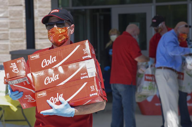 Branden Hall, deli manager, carries soda to a waiting car.