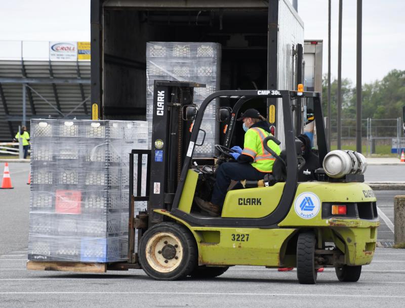 A DelDOT employee unloads a trailer filled with gallons of milk.