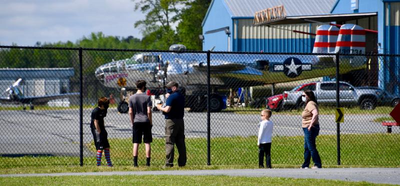 A curious crowd gathers along a fence at Delaware Coastal Airport near Georgetown to watch Panchito, a World War II restored B-25 bomber, roll out of its hangar.