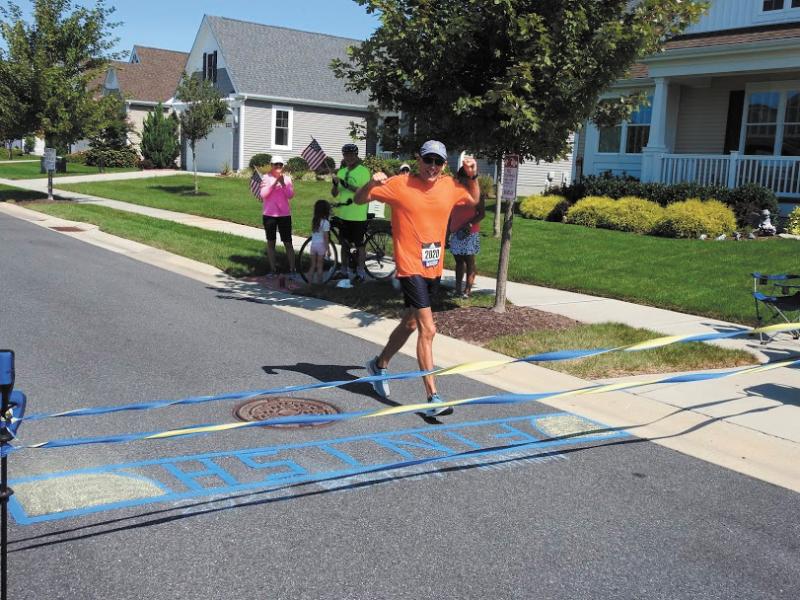 Dave Miller crosses a homemade finish line at the end of his virtual Boston Marathon. PHOTO COURTESY OF GEORGE PERASSO