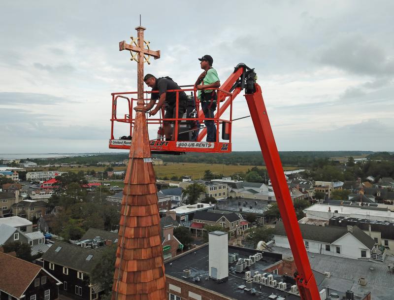 Andrew Lewandowski, left, and Gerardo Hernandez of Bayside Exteriors attach the new cross to the steeple of St. Peter’s Church in downtown Lewes.