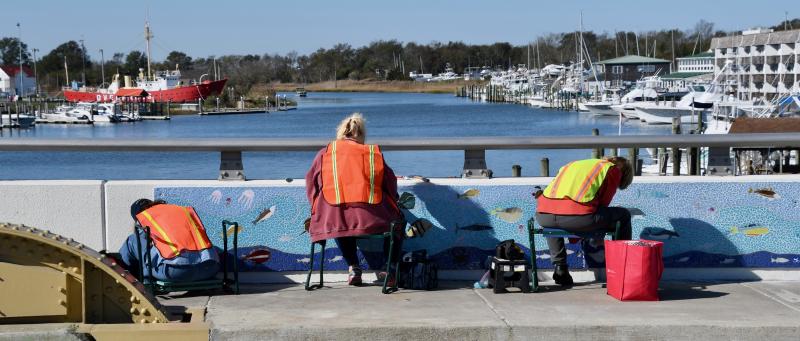 With Lewes Harbor as a backdrop, volunteers (l-r) Mary Pasi, Lisa Sutcliffe and Sue Sandmeyer, project chairwoman, apply finishing touches to the first of four mosaic sections.