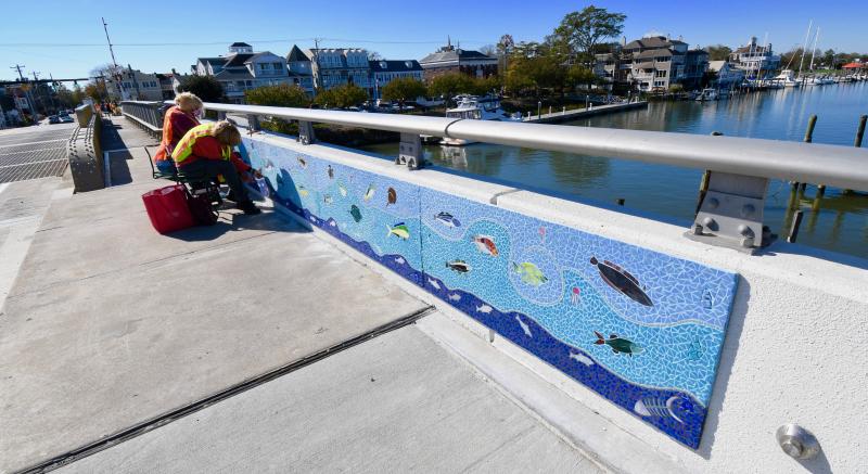 The first section of the Art in Bloom mosaic mural, completed by volunteers, is being placed on the west side of the Lewes drawbridge. RON MACARTHUR PHOTOS