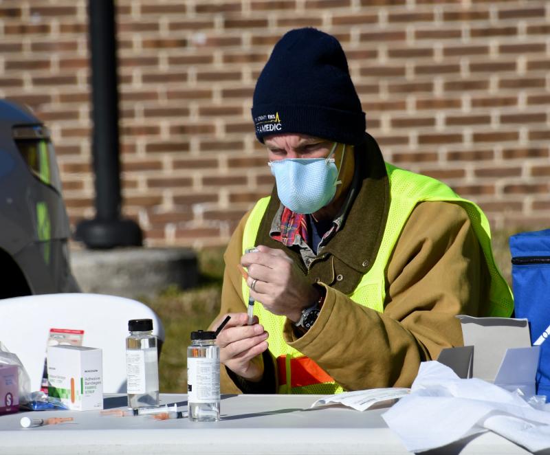A Kent County paramedic transfers COVID-19 vaccine from a vial into a syringe during a mobile vaccination clinic in Dover.