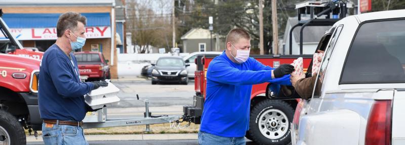 No one would have dreamed there would be an Oyster Eat drive-through. Volunteers Penuel Barrett, left, and Keith Bryan deliver popcorn and two carryout meals during the fire company fundraiser.