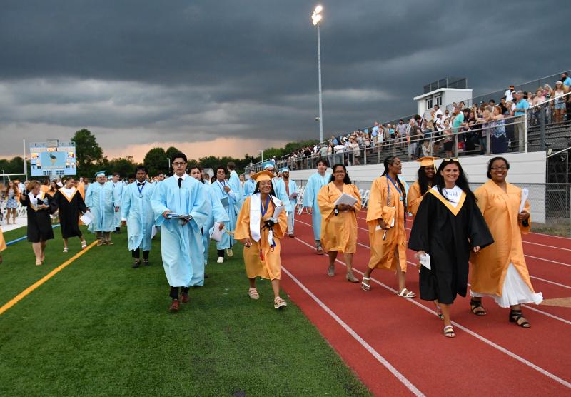 We are out of here. The grads exit the stadium as the rain clouds approach.