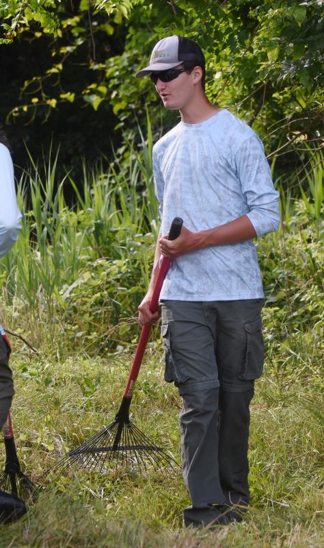 Nicholas Schimmel rakes up debris on the site. Schimmel organized the cleanup as part of his Eagle Scout project.