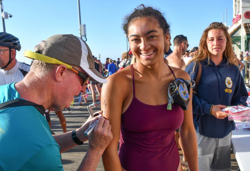 Aya Daisey, right, gets her bib number from race volunteer Rich Tikiob.