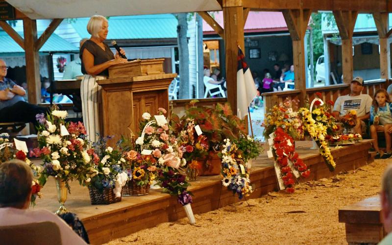 Denise Burton reads the names of memorialized family members and friends remembered with flower arrangements.