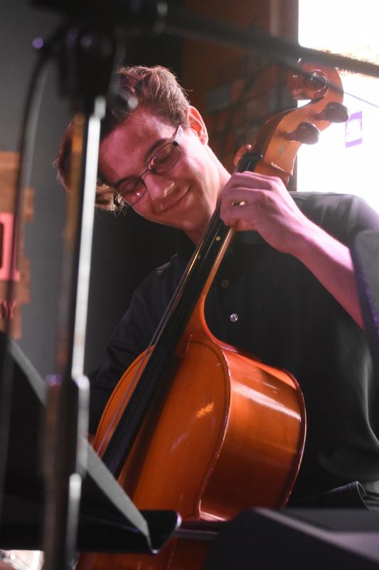Ben Cooper smiles as he plays the cello.