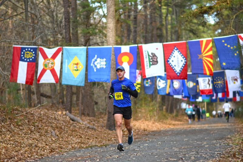 Jerry Tylutki of Sauquoit, N.Y., runs through state flags of all the participants on the way to a second-place finish at the 2018 Rehoboth Seashore Marathon. NICK ROTH PHOTO