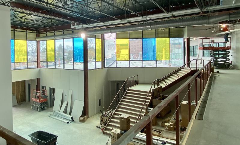 A second-floor outdoor classroom sits behind the Cape-colored blue-and-gold panel windows.