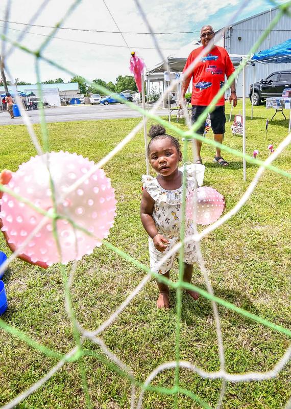 Kamiya Fountain, 18 months, throws a ball to win a prize as grandpop Curtis Johnson looks on.