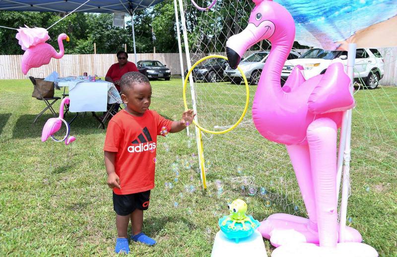 Eli White, 2, grabs some bubbles from the octopus bubble machine at the pink flamingo booth.