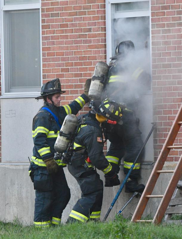 Firefighters work in tandem to gain access to the former school building during a simulated fire.