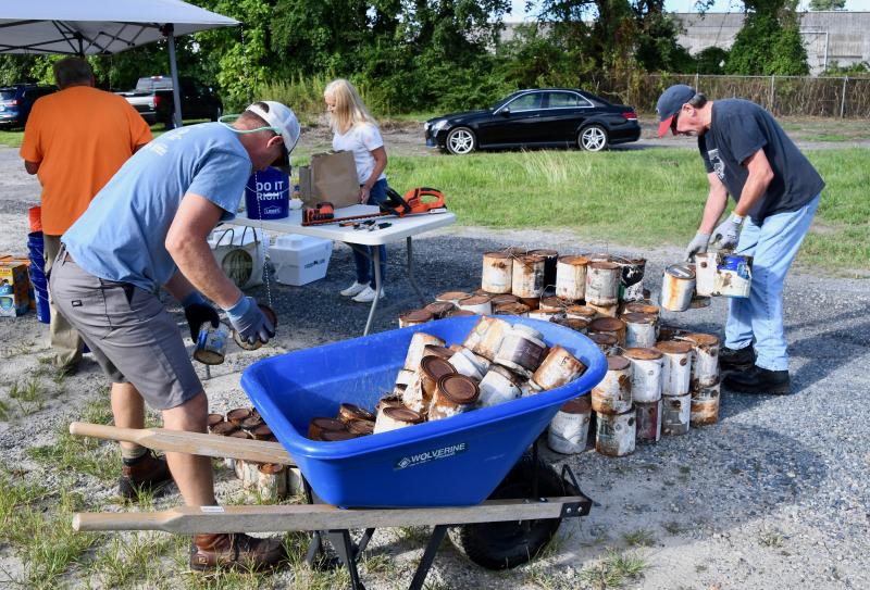 Gilles Lortie, left, and Joe Preston empty out a wheelbarrow filled with old paint cans Aug. 16 during a Dogfish Head Benevolence Day to help clear the property for the Springboard Collaborative Pallet Shelter Village in Georgetown. RON MACARTHUR PHOTOS