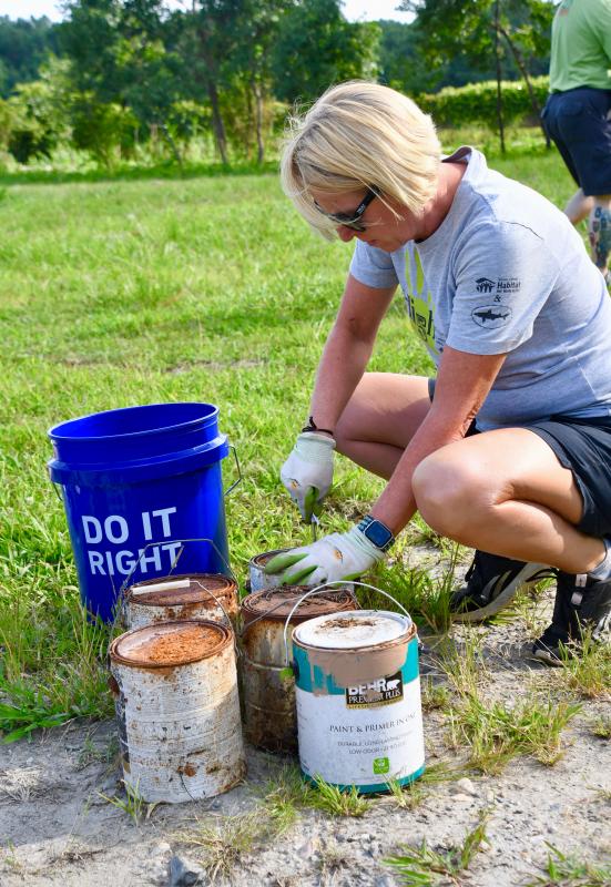 Kristie Lankford pries open gallon cans of old paint in order to mix the contents with kitty litter.