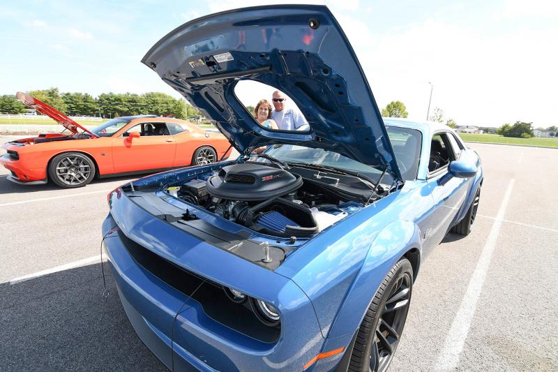 June and Steve Ostenso peeks through the hood on their 2022 Dodge Challenger.