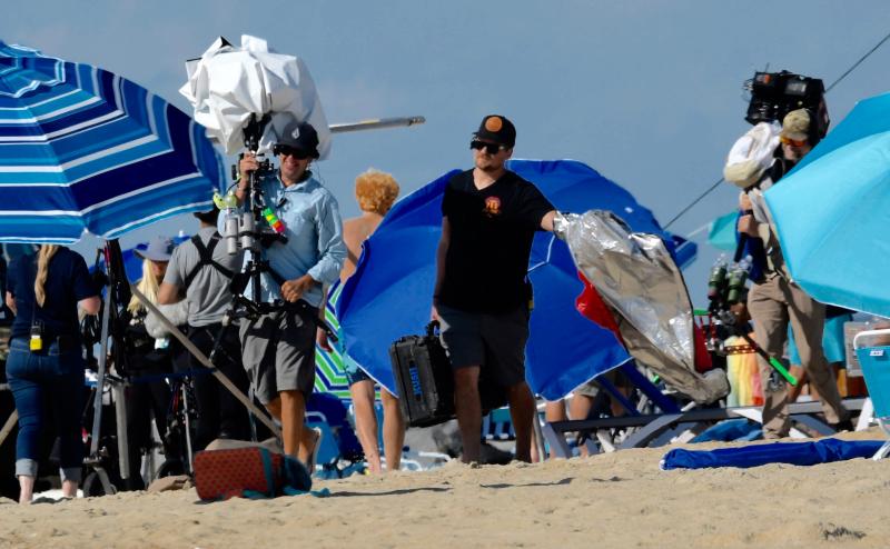 A camera crew moves its equipment to another spot on the beach.