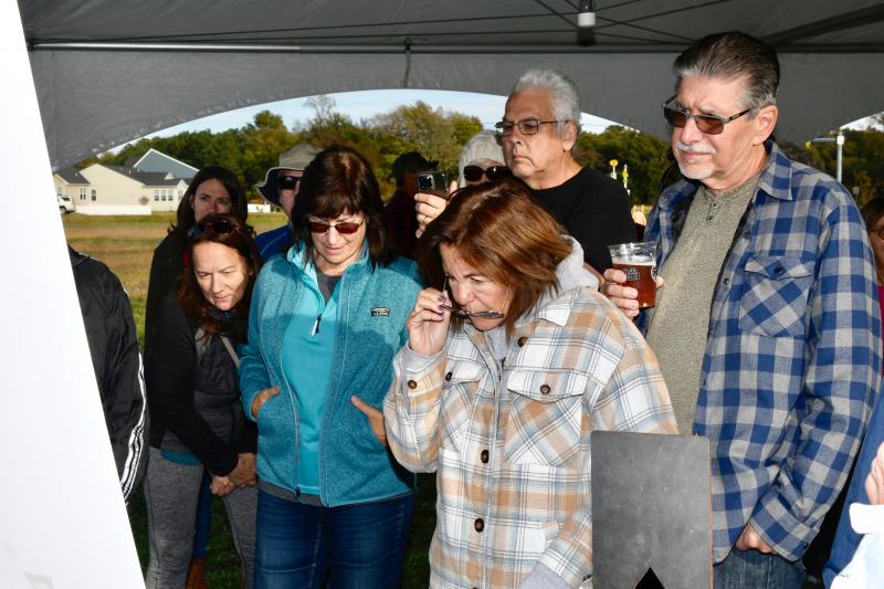 Part of a large crowd gathers under a tent to look at a display of the master plan for Hopkins Preserve.