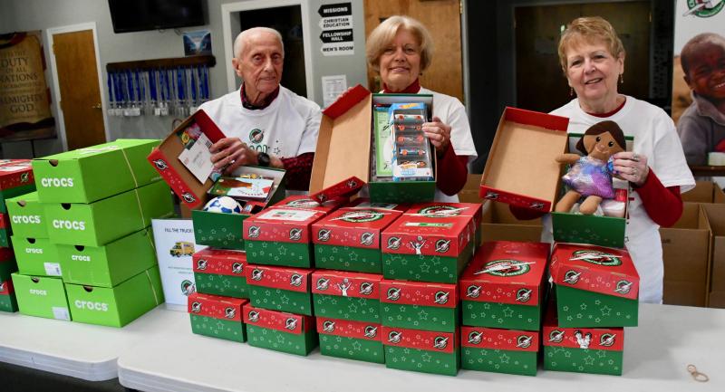 Volunteers at New Covenant Presbyterian Church in 2021 are (l-r) Jack Noel, Renee Weer, project leader, and Sue Eldredge showing what can be packed in the shoeboxes to be distributed worldwide through the Operation Christmas Child project. RON MACARTHUR PHOTO