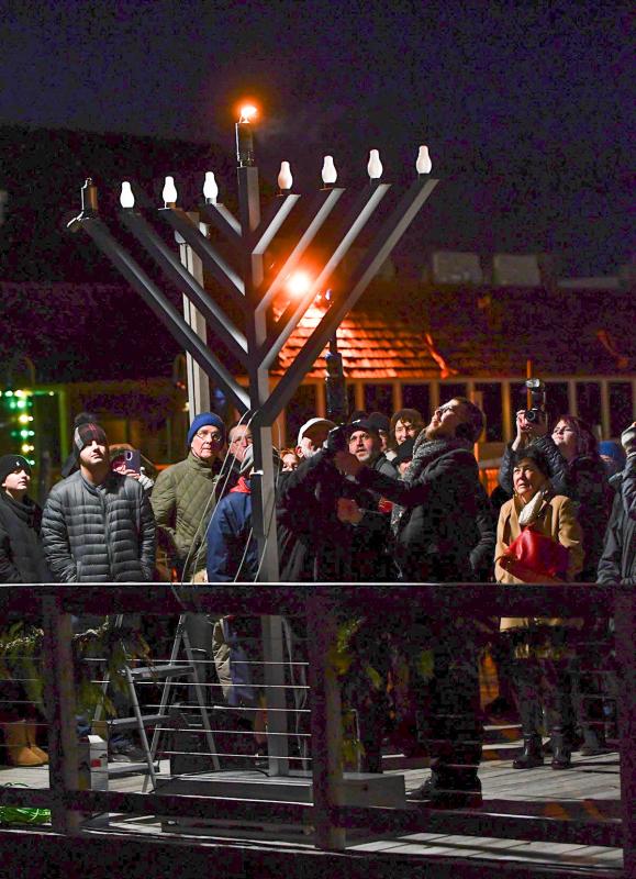 Assisting Rabbi Sholom Vogel with the the lighting of the shamash is Harvey Fruman.