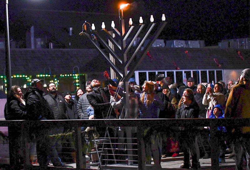 Children, led by Liam Stegall, ignite the first light on the menorah.