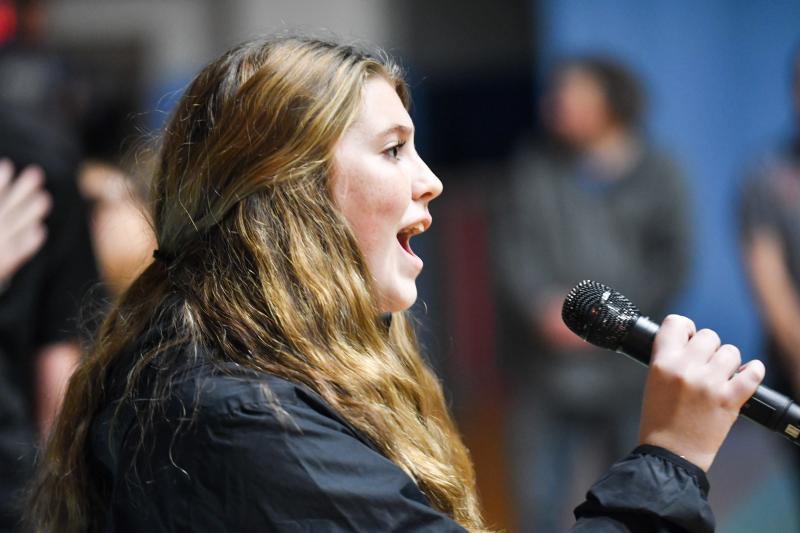 The wrestling crowd stands as sophomore Adria Windish sings the national anthem. DAVE FREDERICK PHOTOS